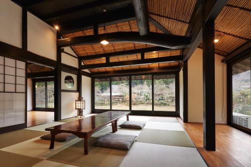 een woonkamer met een tafel en een aantal ramen bij 京都ミヤマシキテイ in Nantan city