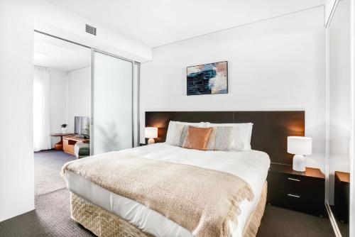 a white bedroom with a large bed and a mirror at 315 Harbour With Ocean Views in Cairns