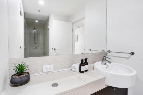 a white bathroom with a sink and a mirror at 315 Harbour With Ocean Views in Cairns