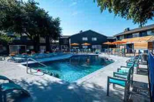 a large swimming pool with benches and umbrellas at Right next to AT&T Stadium Arlington - Luxury Unit in Arlington