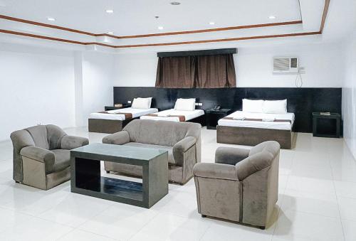 a hotel room with two beds and a couch and chairs at Check Inn Bacolod by RedDoorz in Bacolod