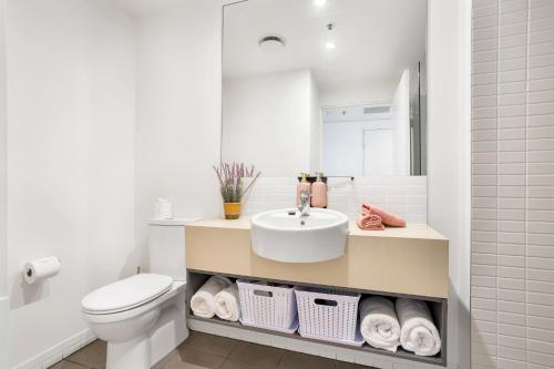a white bathroom with a sink and a toilet at Marina View Queen Bed Studio Apartment Pool & Gym in Cairns