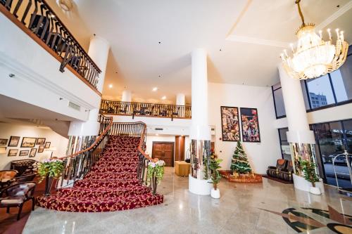 a large lobby with a staircase with red chairs at MITC Hotel in Malacca