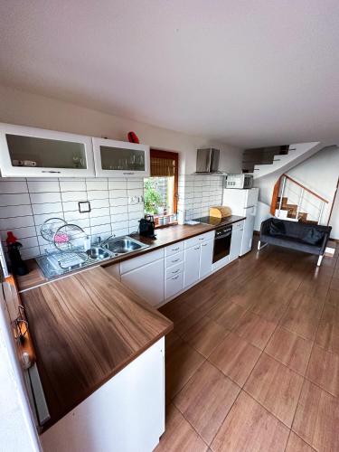 a kitchen with white cabinets and a wooden floor at Panoráma Csopak in Csopak