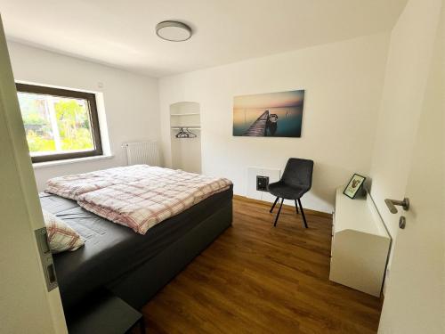 ein Schlafzimmer mit einem Bett und einem Stuhl darin in der Unterkunft Modern Apartment Wissenbach 2 in Eschenburg