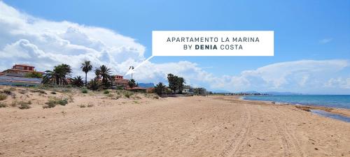 an empty beach with palm trees and houses on it at Apartamento La Marina by DENIA COSTA in Denia