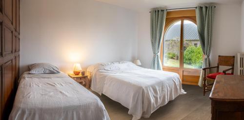 1 dormitorio con 2 camas y ventana en Magnifique longère bretonne., en Lanmeur
