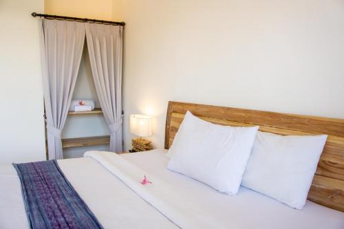 a bedroom with a bed with white sheets and pillows at The Lucky Canggu in Canggu