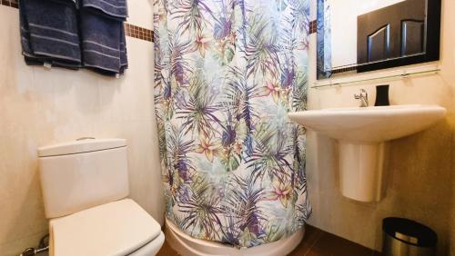 a bathroom with a shower curtain with a toilet and a sink at Villa Agata Mauritius in Mont Choisy
