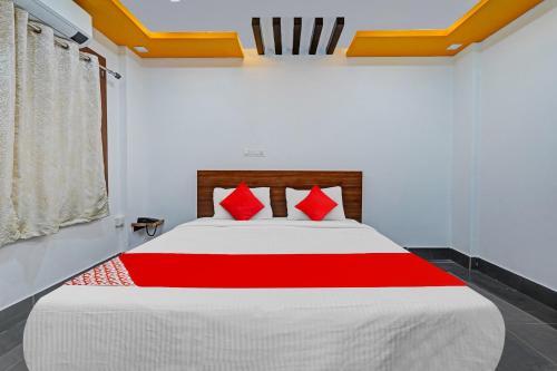 OYO Flagship Vasudha inn, Hoskote في بانغالور: غرفة نوم بسرير كبير ومخدات حمراء