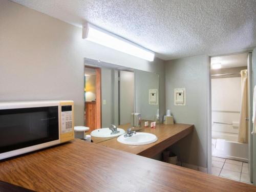 a bathroom with a sink and a microwave at OYO Hotel Hutchinson KS West 4th Ave in Hutchinson