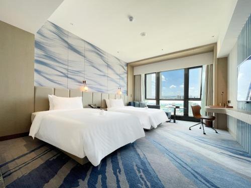 a hotel room with three beds and a large window at White Swan VYV Hotel, Foshan in Foshan