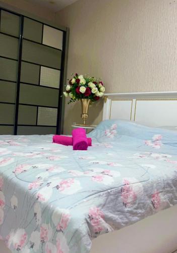 een groot bed met een vaas met bloemen erop bij Dzora Vista Alam 3 in Shah Alam