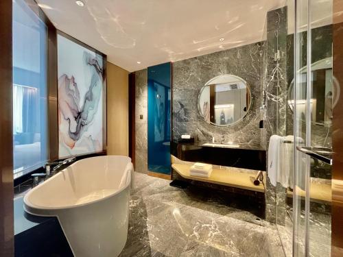 W łazience znajduje się wanna, umywalka i lustro. w obiekcie White Swan VYV Hotel, Foshan w mieście Foshan