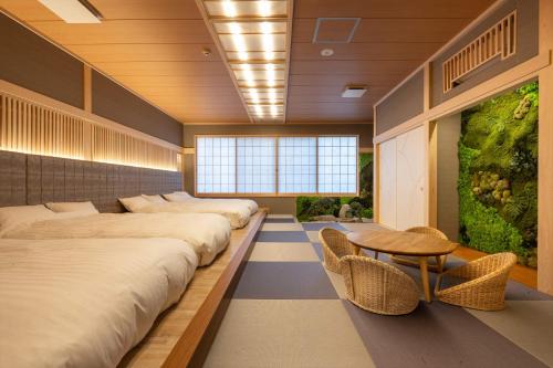uma fila de camas num quarto com uma mesa e cadeiras em Yumura Onsen MIDORIYA em Yumura