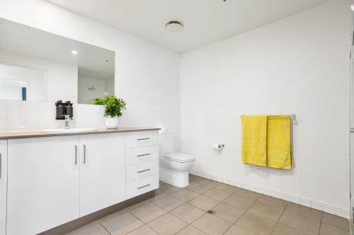 een witte badkamer met een toilet en een gele handdoek bij Luxury 1BR Apartment @ Harbour Lights Cairns in Cairns