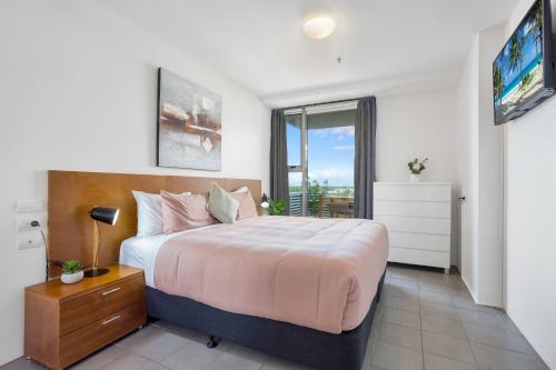 een slaapkamer met een groot bed en een televisie bij Luxury 1BR Apartment @ Harbour Lights Cairns in Cairns