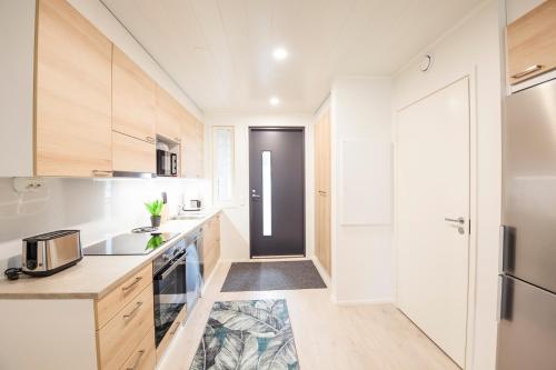a kitchen with white cabinets and a black door at Tuomenkartano Apartments by Hiekka Booking in Kalajoki