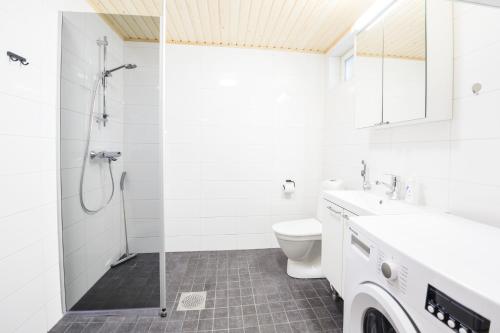 a white bathroom with a shower and a toilet at Tuomenkartano Apartments by Hiekka Booking in Kalajoki