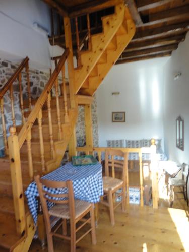 a dining room with a table and wooden stairs at The Castle's Key in Volissos