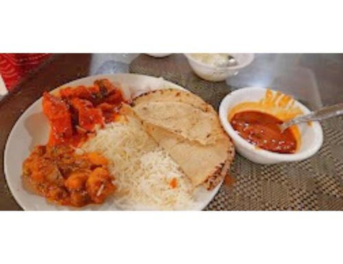 a plate of food with rice and a bowl of salsa at Hotel Raj Palace, Amritsar in Amritsar