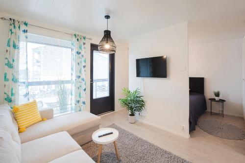a living room with a couch and a tv at Tuomenkartano Apartments by Hiekka Booking in Kalajoki