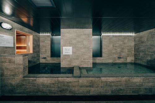 a room with a tub with a clock on the wall at 3s HOTEL HIRATSUKA in Hiratsuka