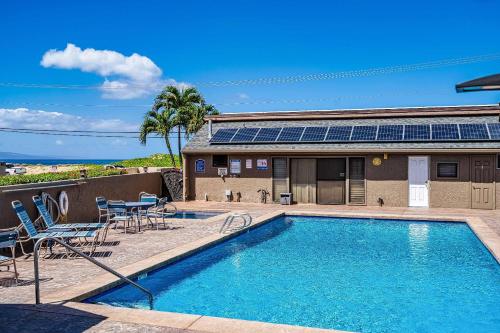 a swimming pool with chairs and a house with solar panels at 103 Kihei Holiday in Kihei