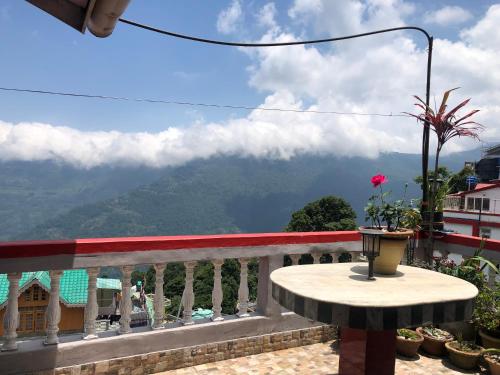 balcón con mesa y vistas a las montañas en Raibas Homestay, en Darjeeling