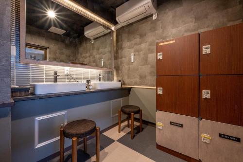 een badkamer met een wastafel en 2 barkrukken bij Yumura Onsen MIDORIYA in Yumura