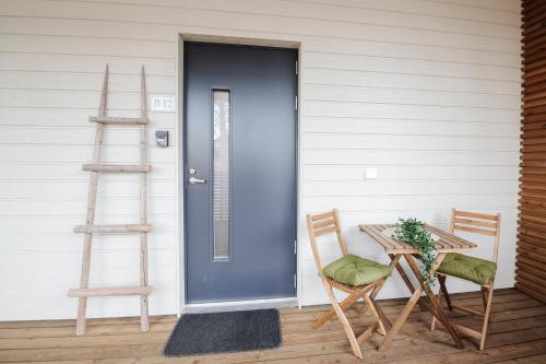 a blue door on a porch with a table and chairs at Tuomenkartano Apartments by Hiekka Booking in Kalajoki