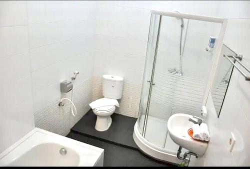 a white bathroom with a toilet and a sink at Ohulu Guesthouse in Medan