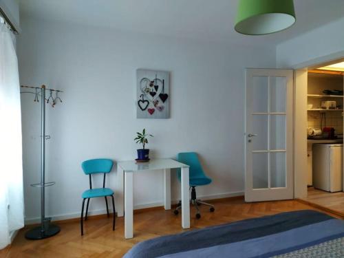 Habitación con mesa y 2 sillas azules en 4 minutes from Lausanne Train Station, en Lausana