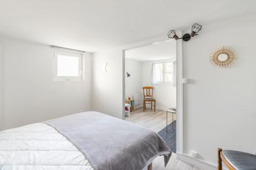 a white bedroom with a bed and a mirror at Appartement 200 m plage avec terrasse et jardin in Royan