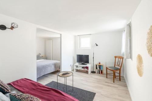 a white room with a bed and a television at Appartement 200 m plage avec terrasse et jardin in Royan