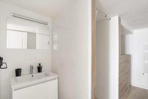 a white bathroom with a sink and a mirror at Appartement 200 m plage avec terrasse et jardin in Royan