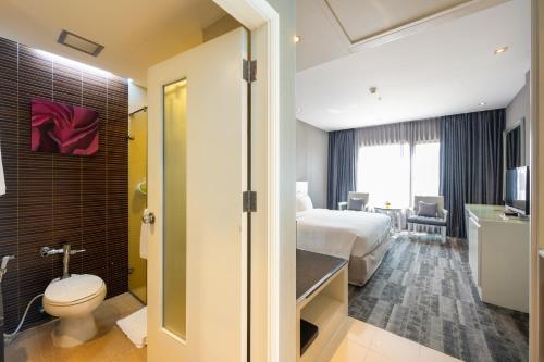 a hotel room with a bed and a bathroom at Grand Richmond Stylish Convention Hotel in Nonthaburi