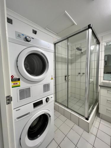 a laundry room with two washing machines and a shower at Marina View Holiday Apartment - Beautiful Views in Larrakeyah