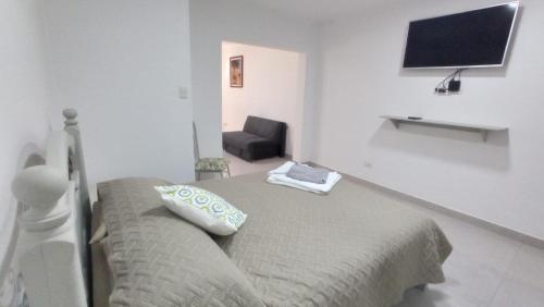 a bedroom with a bed and a chair and a flat screen tv at Apartamento Privado SOL in Tarija