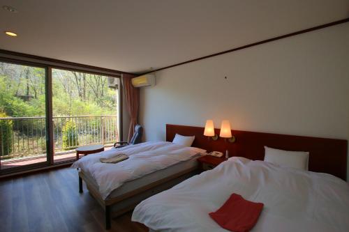a hotel room with two beds and a balcony at hokkein-onsen kougen-terrace in Kokonoe