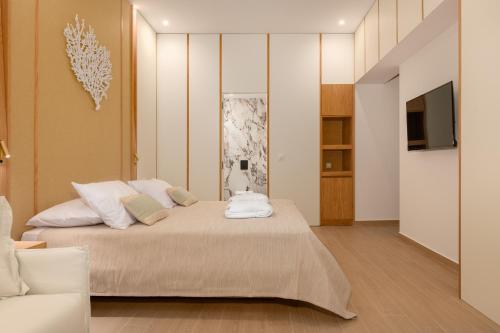 a bedroom with a bed with white pillows and a television at The 12th City Hotel in Rhodes Town