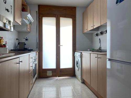 una cocina con armarios de madera y una puerta en Apartamentos Alcañiz, Blanca, en Alcañiz