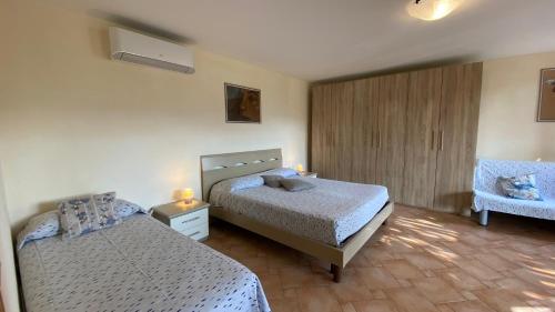a bedroom with two beds and a chair at Villetta di Rosa in Procchio