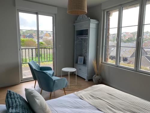 a bedroom with a bed and a chair and windows at LE NID SUR LA FALAISE in Ault