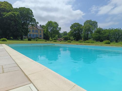 uma grande piscina azul em frente a uma casa em Le Château des Portes 