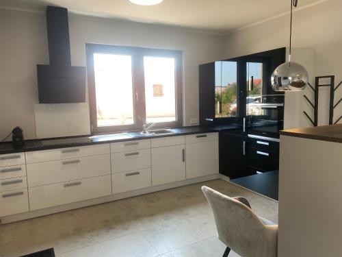 una cocina con armarios blancos, fregadero y ventanas en Apartment Loch 10, 
