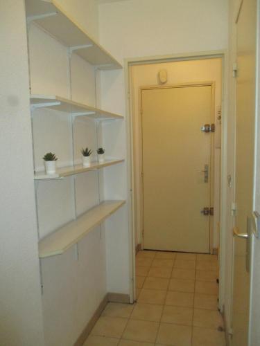 un couloir avec des étagères et une porte menant à une chambre dans l'établissement Studio au calme à 5mn de la mer et de toutes attractions de la ville, à Cannes