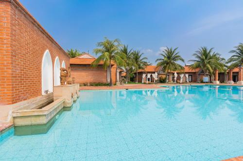 a large swimming pool next to a brick building at TTC Resort Ninh Thuan in Phan Rang–Tháp Chàm