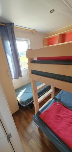 une chambre avec deux lits superposés et une fenêtre dans l'établissement MH135 camping TOHAPI NOVELA - Mobil home 5p climatisé -, à Port-la-Nouvelle