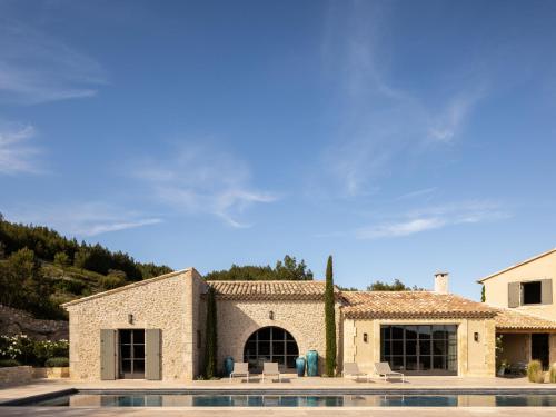 - un bâtiment en pierre avec une piscine en face dans l'établissement Terres Rouges, à Maussane-les-Alpilles